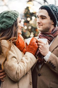 Couple with cups of mulled wine as drink on Christmas market