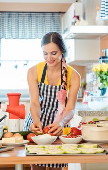 Woman putting colorful vegetables in a bowl to make salad