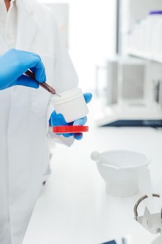 Pharmacist mixing drug on order in laboratory wearing protective clothing