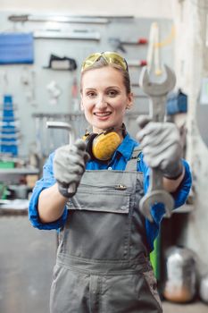 Woman mechanic showing tools to the camera holding wrench in her hand