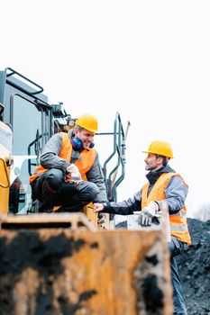 Foreman showing worker in open-cast mining pit direction with arm stretched