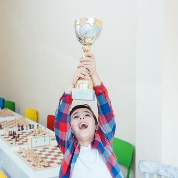 Boy showing trophy he has won in chess tournament in excitement
