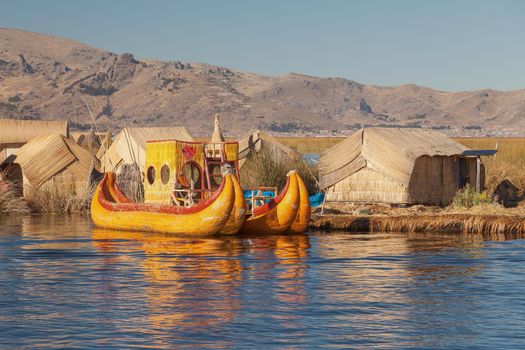 Reed boat on Island of Uros. Those are floating islands on lake Titicaca located between Peru and Bolivia. Colorful image with yellow boat and clear blue sky.