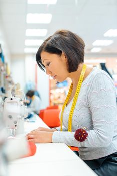 Alterations tailor in her studio working in some clothes with sewing machine