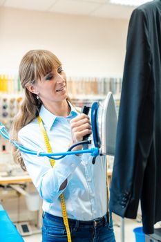 Woman in textile cleaner ironing clothes in the shop