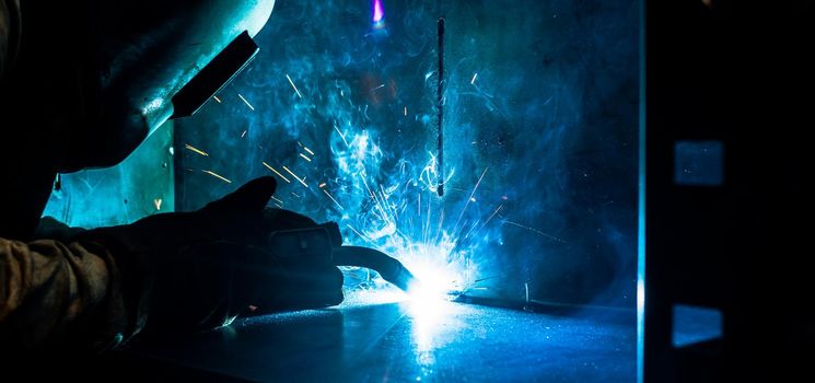 Welder working in factory with lots of sparks flying
