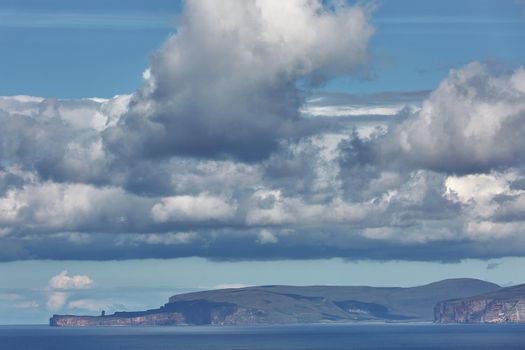 Orney cliffs with dramatic sky seen from John o'Groats over Atlantic ocean