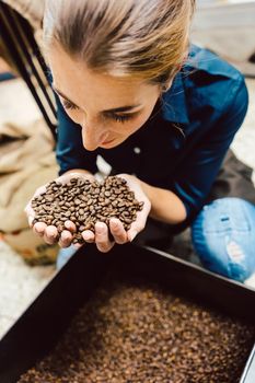 Barista woman testing the aroma of fresh coffee beans sniffing