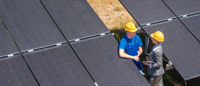 Two people standing amid solar cells in a power plant inspecting the modules