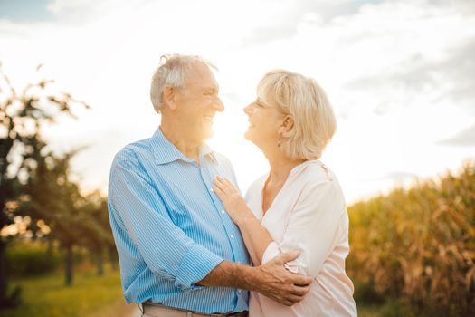 Senior couple hugging each other outdoors during sunset