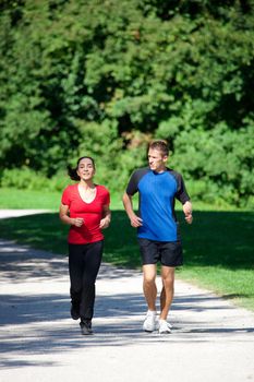 Mature woman is jogging in her free time with her young personal trainer on a sunny and warm day