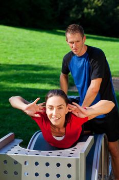 Mature woman does exercises with her personal trainer, having a lot of fun on a sunny day