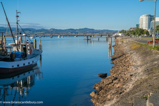 Tauranga downtown Strand waterfront from old wharf with fishing boat and leading line of reclaimed water's edge.