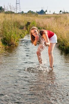 Woman standing in a little creek with her ankles in the water, the cold water is refreshing in the summer heat