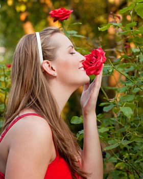 Woman doing garden work sniffing at the roses at beautifully sunny day