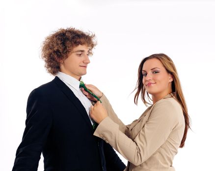 Business people standing in a studio, she is binding his tie
