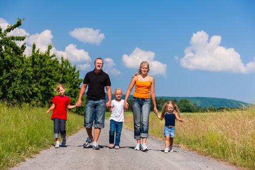 Family walking down a rural path on bright summer day