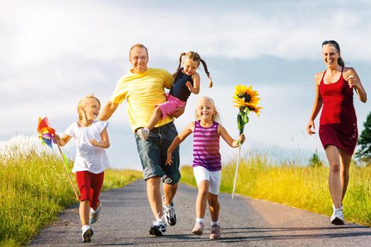 Family with three kids running down a hill in summer