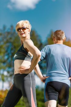 senior couple in jogging gear doing sport and physical exercise outdoors, stretching and gymnastics