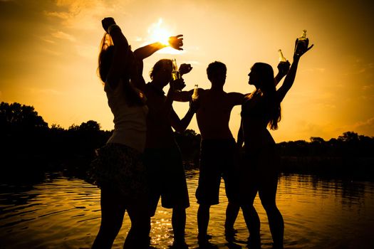 People feeling free in the sunset having a summer party in the water