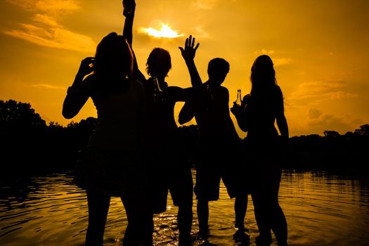 People feeling free in the sunset having a summer party in the water