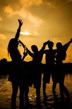 People feeling free in the sunset having a summer party in the water