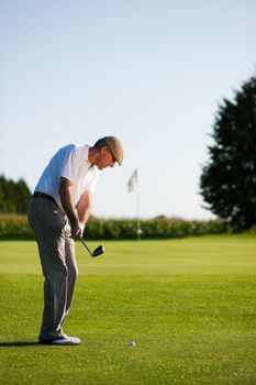 Senior golfer doing a golf stroke, he is playing on a wonderful summer afternoon