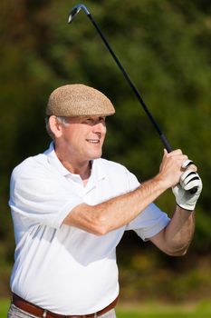 Golfer - only torso to be seen - doing a golf stroke, he is playing on a wonderful summer afternoon