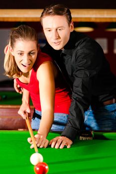 Couple (man and woman) in a billiard hall playing snooker