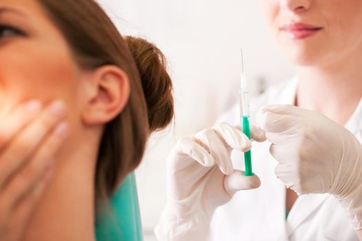 At the dentist - a female patient is getting ready to receive a anesthetization syringe (focus on syringe)