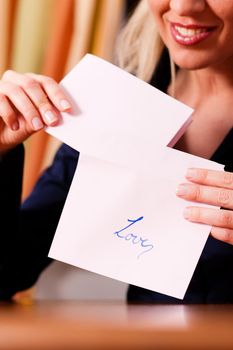 Woman is putting a love letter in an envelope