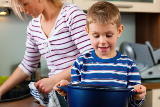 Family cooking in their kitchen - the son is looking into the pan