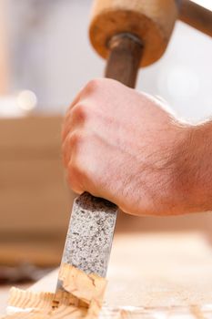 Carpenter working with a chisel in his workshop; close-up on chisel