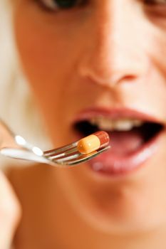 Woman eating nutritional supplement - symbolized by a pill on a fork 