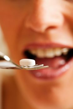 Woman eating nutritional supplement - symbolized by a pill on a fork 