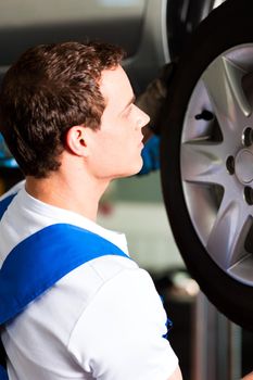 Auto mechanic in his workshop changing tires or rims