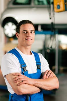 Auto mechanic standing in his workshop in front of a car on a hoist