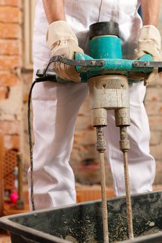 Construction worker mixing concrete or grout with a hand mixer