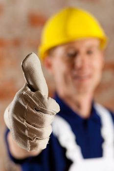 Friendly and reliable construction worker giving thumbs up, focus on thumb