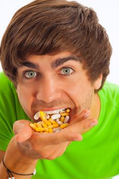 Young man is feeding himself pills and drugs, close-up