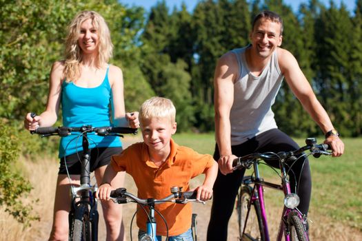 Family with child on their bikes on a summer day in sport outfit, they are exercising