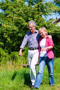 Visibly happy mature or senior couple outdoors arm in arm having a walk