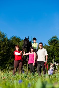 Family with children posing with a horse, one child riding the animal