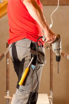 construction worker with hand drill standing on a scaffold