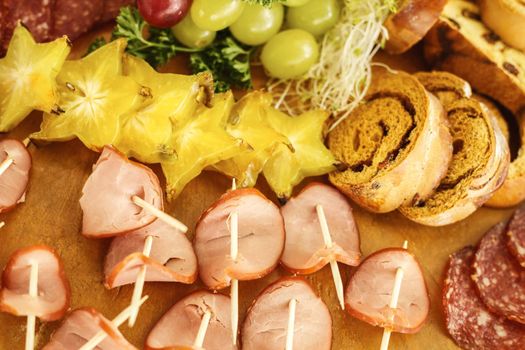 Catering service with various fruits and sausages on wood