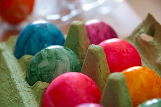 Beautiful colored eggs in a cardboard box