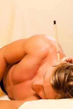 Man in wellness and spa setting with ear candles having an alternative therapy session