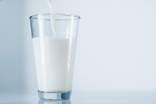 Dairy, healthy nutrition and breakfast concept - World Milk Day, pouring into glass on marble table