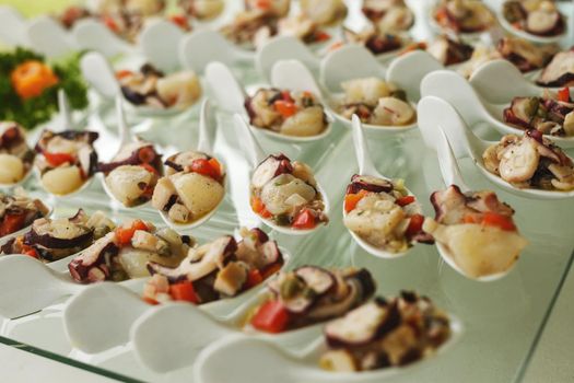 Seafood served on porcelain spoons and glass table