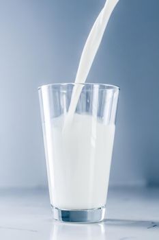 Dairy, healthy nutrition and breakfast concept - World Milk Day, pouring into glass on marble table